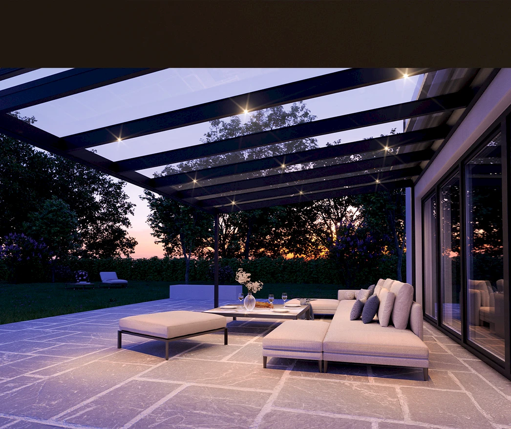 Stimmungsvolle Terrasse am Abend unter einem Glasdach mit integrierter LED-Beleuchtung und gemütlicher Lounge.
