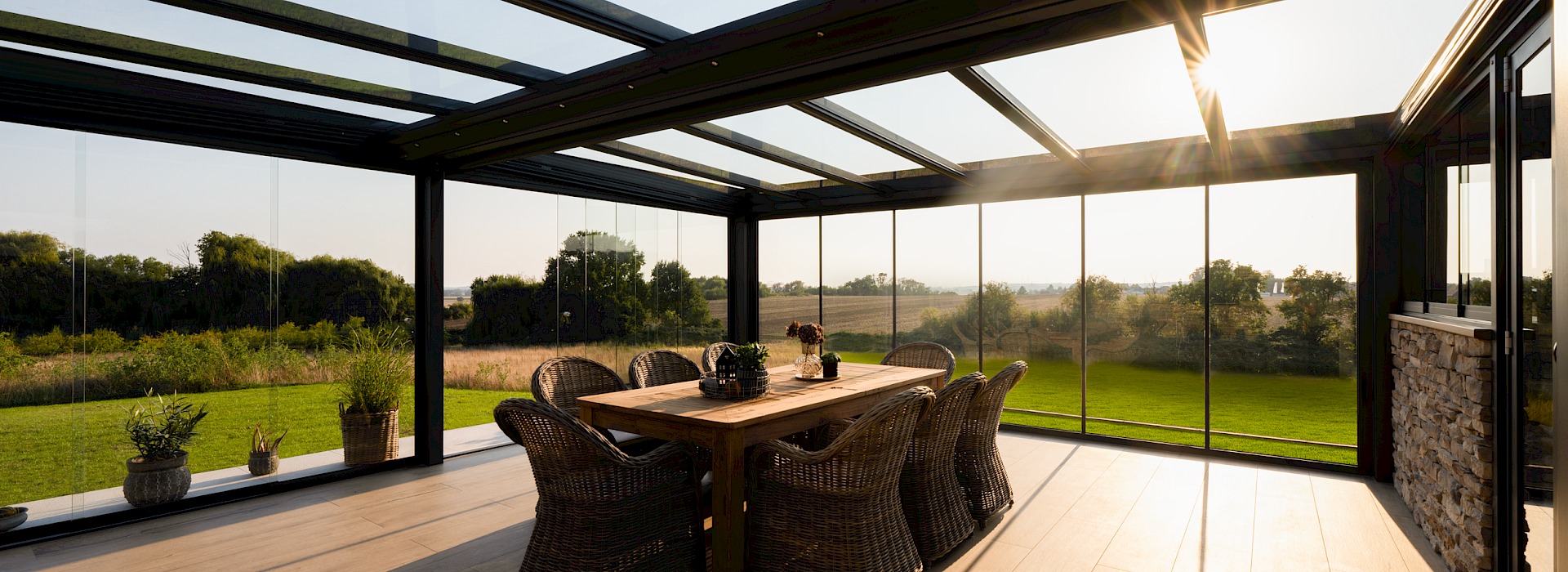 Einfamilienhaus mit eleganter Glas-Terrassenüberdachung und seitlichen Schiebeelementen, modernes Outdoor-Wohnzimmer