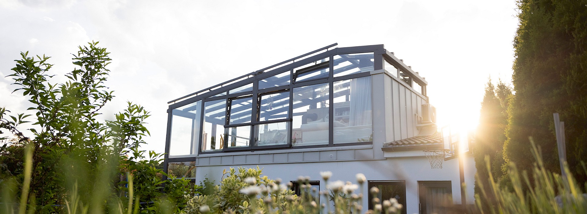 Einfamilienhaus mit eleganter Glas-Terrassenüberdachung und seitlichen Schiebeelementen, modernes Outdoor-Wohnzimmer