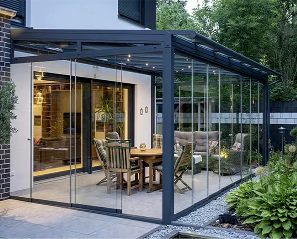 Eleganter Sommergarten mit anthrazitfarbenen Aluminiumprofilen, Glasdach und gemütlichem Essbereich mit Beleuchtung.