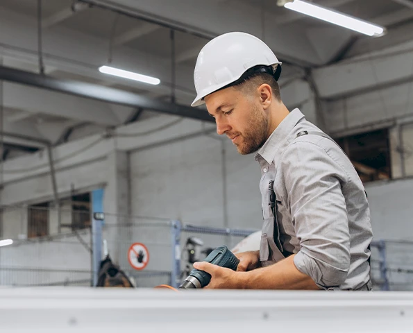 Handwerker befestigt präzise ein Aluminiumprofil mit Akkuschrauber, Detailaufnahme während der Montage.