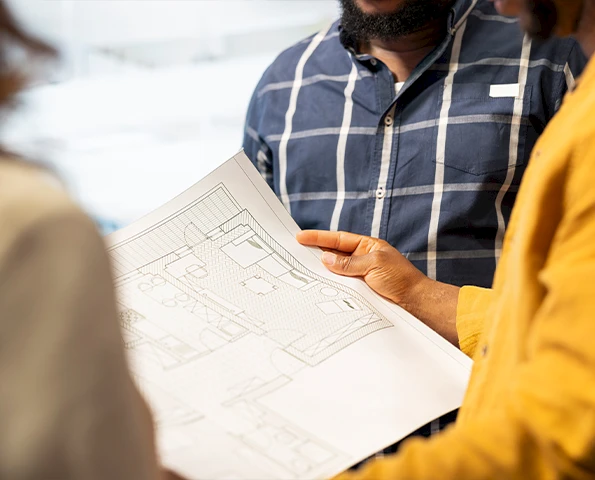 Team bespricht detaillierte Baupläne und Konstruktionszeichnungen für ein Bau- oder Ausbauprojekt.
