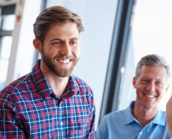 Zwei Männer im Gespräch, einer lacht freundlich – Beratungssituation in modernem Büro.