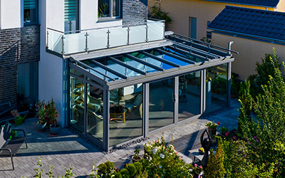 Großzügiger Sommergarten mit Aluminium-Glasdach und Ganzglasschiebeanlagen an Einfamilienhaus