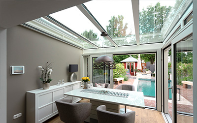 Heller Wohnraum mit Glasdach-Erweiterung und Blick auf Terrasse und Gartenanlage