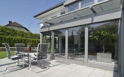 Wintergarten mit Aluminiumkonstruktion und Senkrechtmarkise an moderner Hausfassade