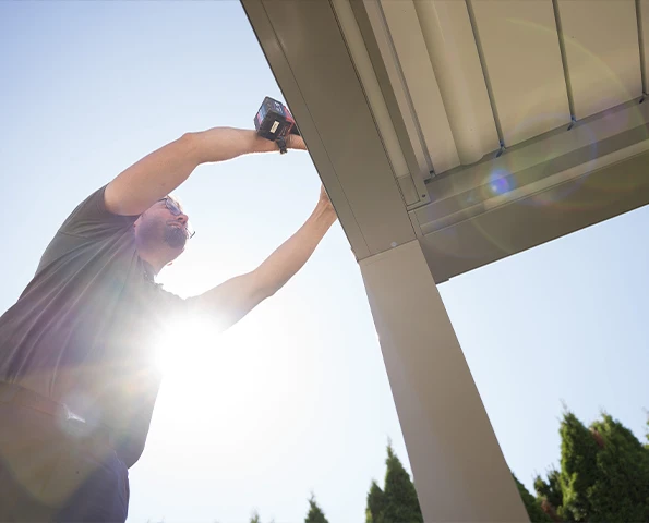 Monteur installiert Aluminium-Lamellendach an moderner Terrasse