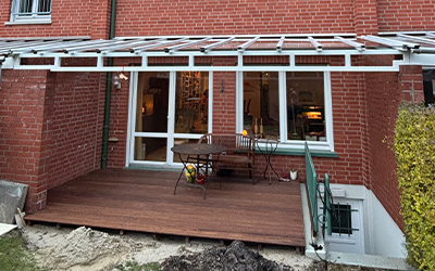 Terrassenüberdachung mit Aluminiumkonstruktion über Holzterrasse am Reihenhaus