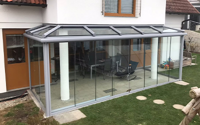 Kaltwintergarten aus Glas als geschützter Anbau an ein Wohnhaus mit viel Tageslicht