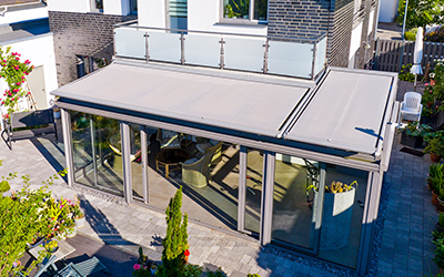 Wintergarten mit Sonnenschutz-Markise und umlaufender Verglasung für ganzjährige Nutzung