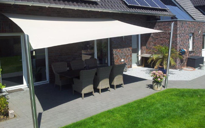 Großflächige Sonnensegel-Markise über Terrasse mit Sitzbereich im Garten