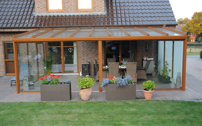 Großzügiger Sommergarten mit Glasdach, Holzoptik-Rahmen und seitlicher Verglasung an einem Wohnhaus