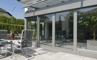 Seitliche Glasschiebeelemente einer Terrassenüberdachung mit Blick auf Terrasse und Garten