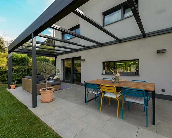 Freistehendes Aluminium-Lamellendach an moderner Hausfassade mit regulierbaren Lamellen
