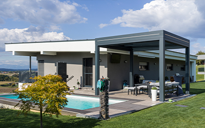 Moderne Terrassenüberdachung mit Glaswänden an einem Haus mit Pool und Garten