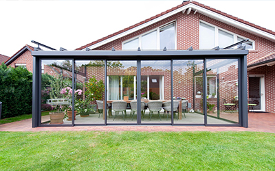 Freistehender Sommergarten mit Glasschiebewänden und dunklen Aluminiumprofilen