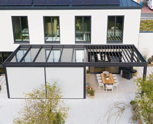 Moderne Terrassenüberdachung mit Glaswänden und Lounge-Bereich an einem Backsteinhaus