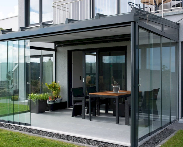 Verglaster Sommergarten mit dunklen Aluminiumprofilen, Glasschiebewänden und Essbereich