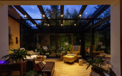 Verglaster Wintergarten mit Aluminiumprofilen und integrierter Beleuchtung am Abend
