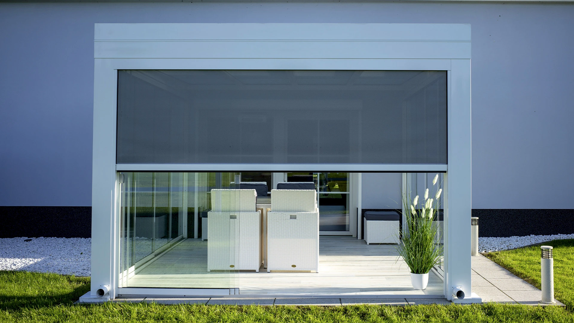 Sommergarten an einem Reihenhaus mit schmaler Terrasse, rahmenlosen Glasschiebetüren und platzsparendem Essbereich.